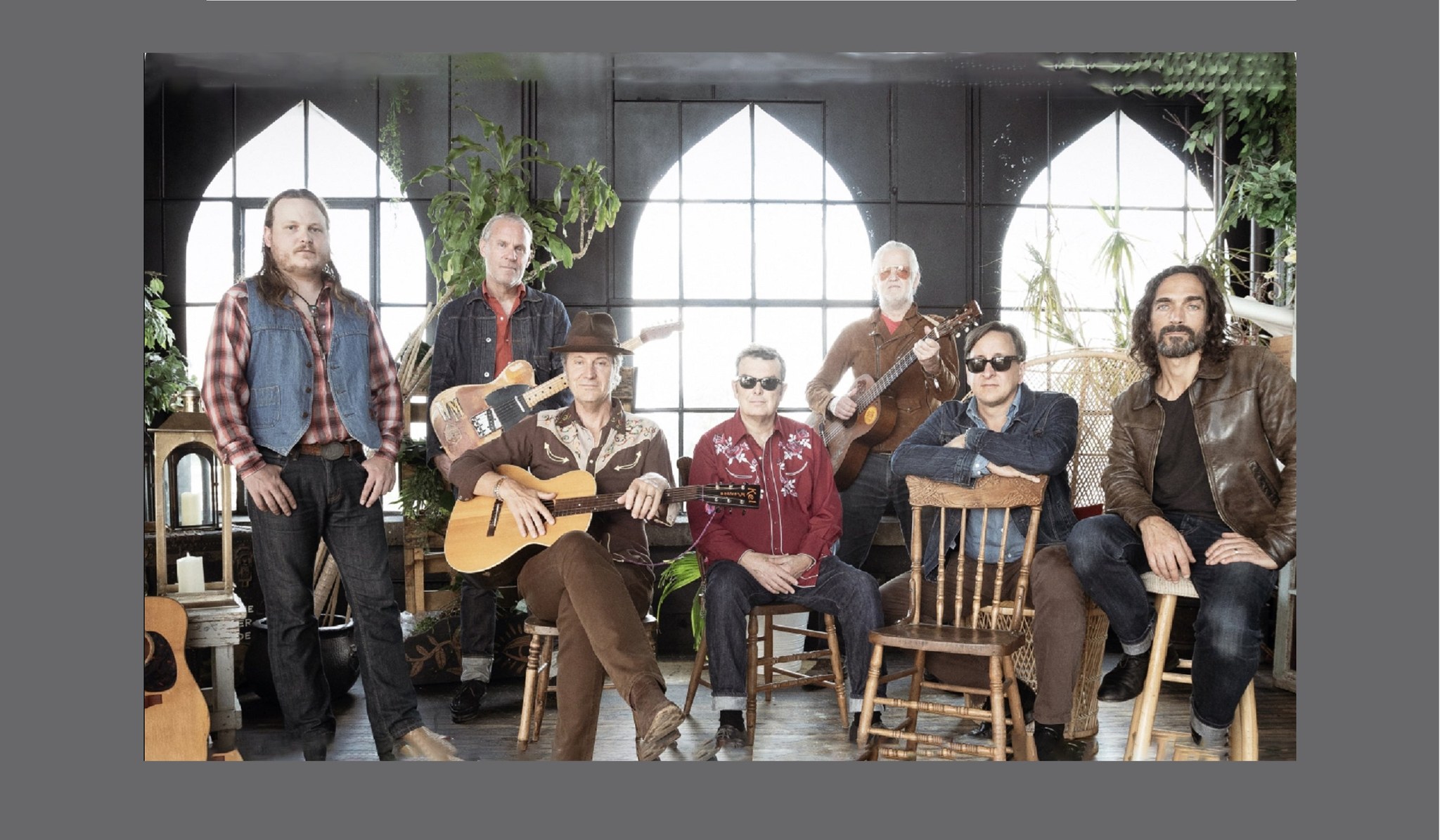 image of 7 people, 4 guitars and wooden chairs