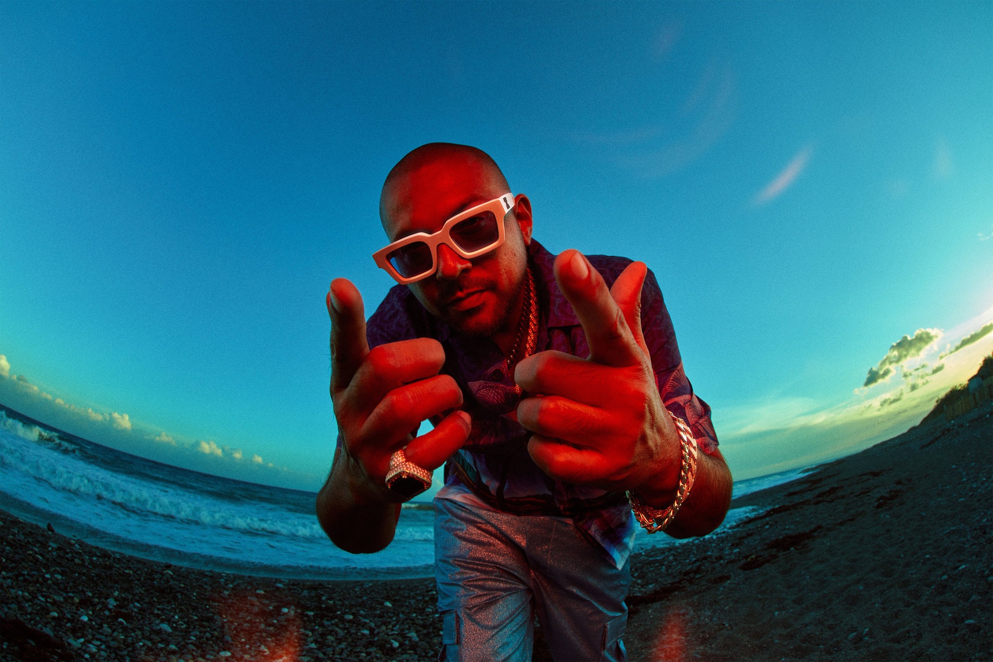 image of person with sunglasses, ring and bracelet next to water